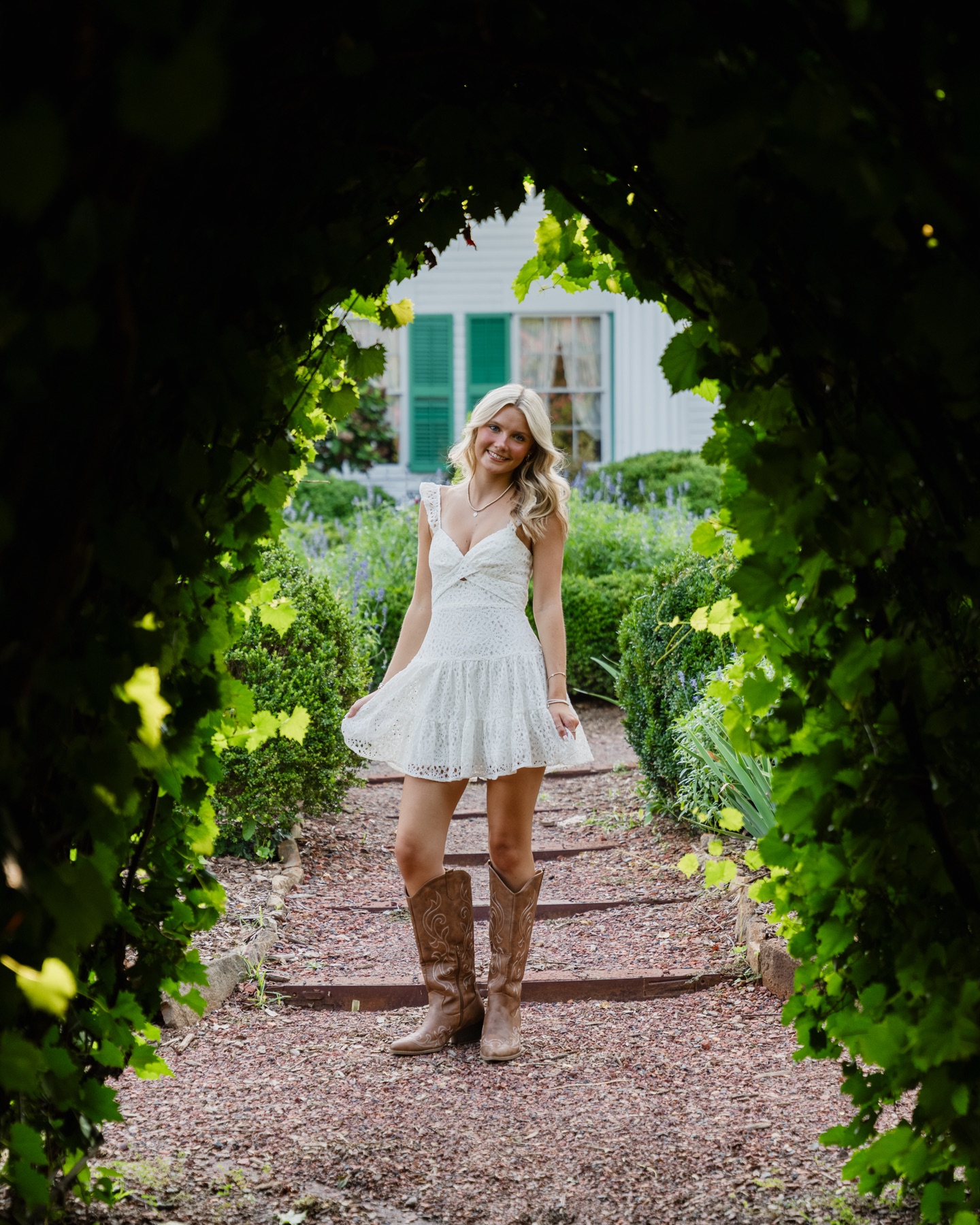 Senior portrait framed by a leafy garden arch