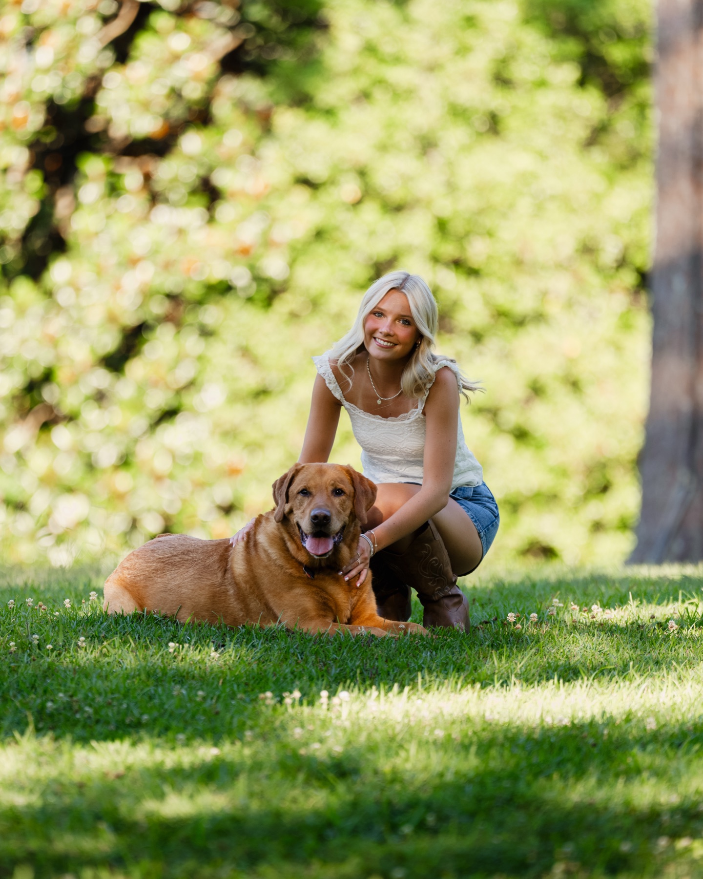 Senior portrait with a dog on a sunlit lawn
